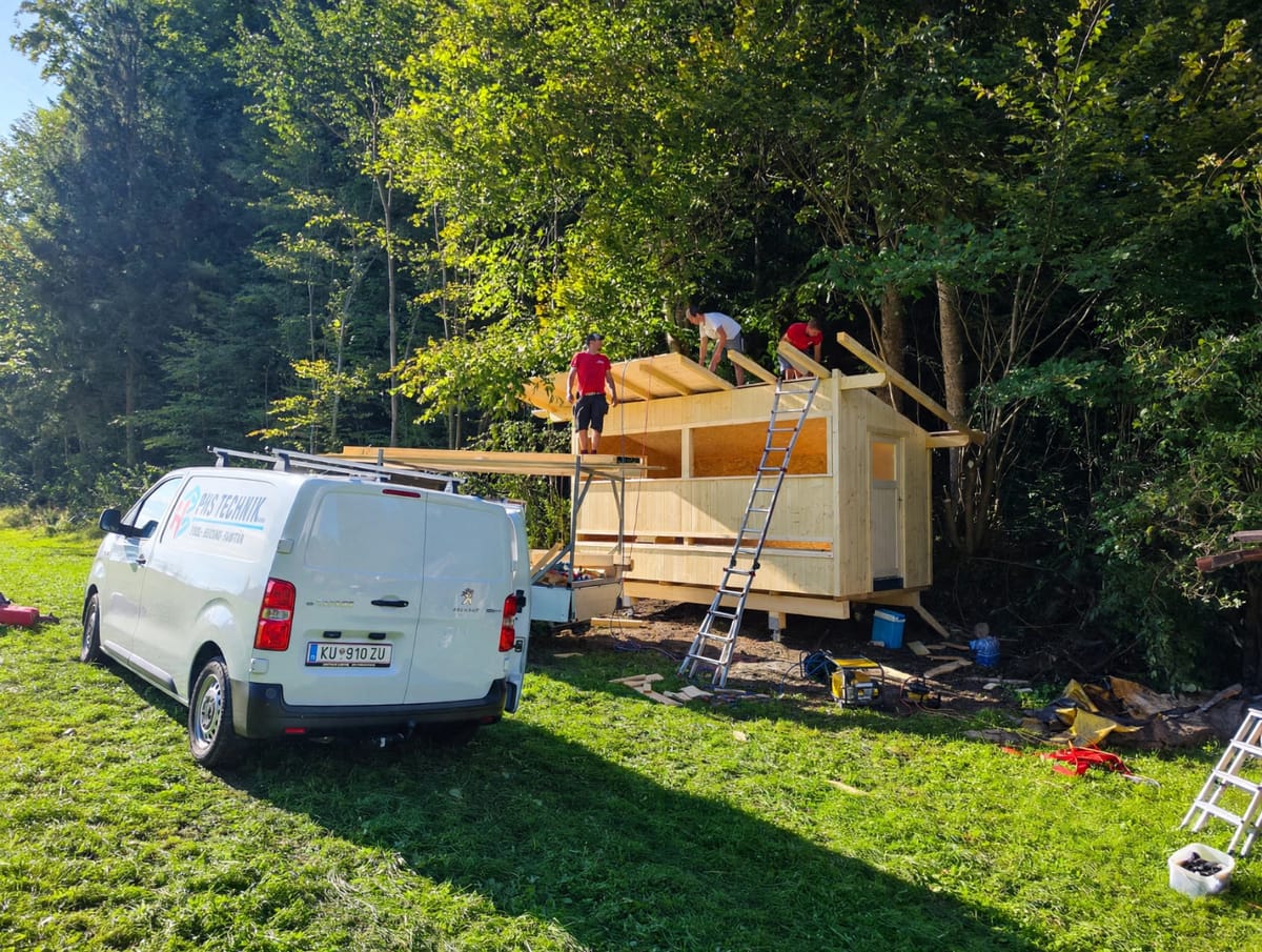 Freunde beim Bau des Bienenhauses, mit Leiter und Lieferwagen auf der Wiese